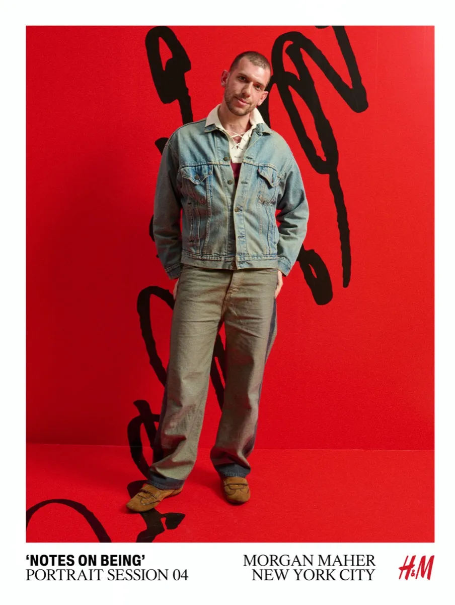 H&M Notes on Being portrait session by Morgan Maher — man in denim jacket posing against red backdrop with black brushstroke art in New York City