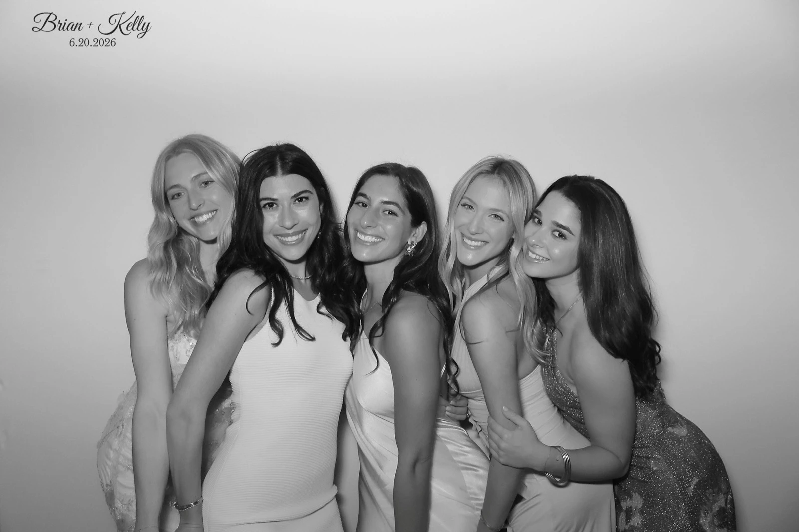 Black and white glam booth photo of wedding guests on a white backdrop