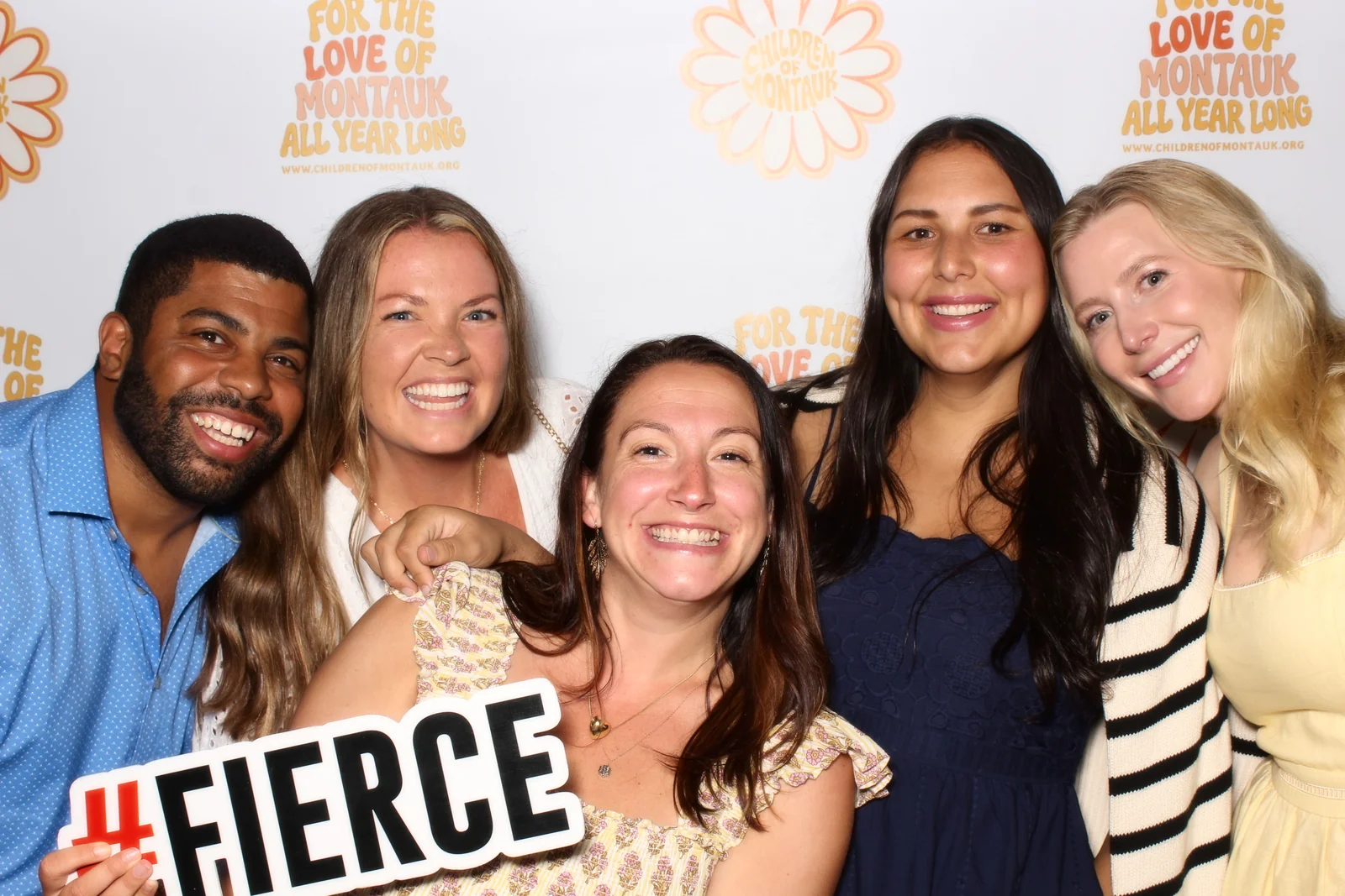 Brand activation photo booth rental NYC — guests at a branded step and repeat backdrop with a hashtag sign