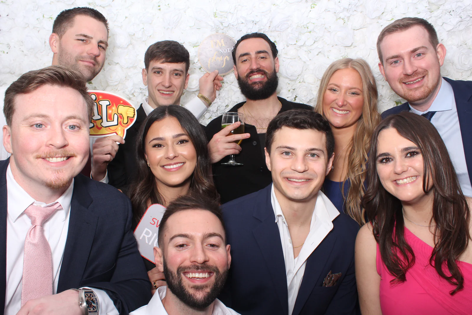 Flower wall photo booth rental NYC — group of nine guests at a white rose flower wall