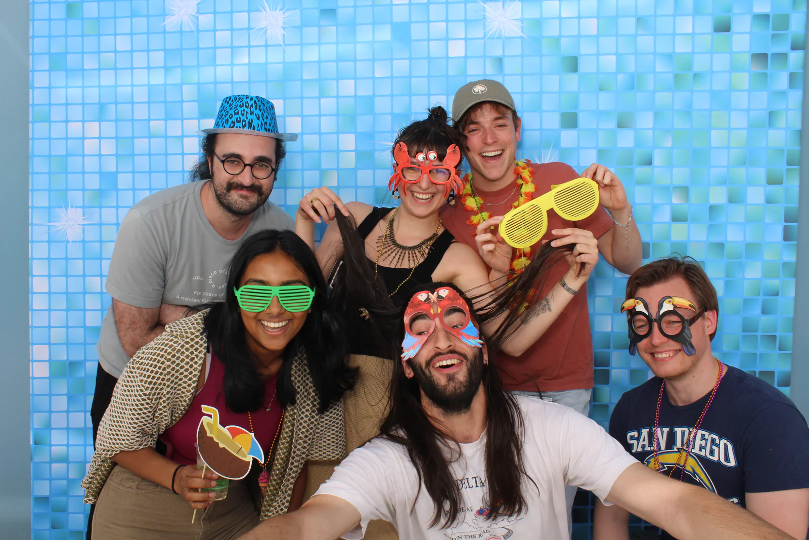 Open air photo booth rental NYC — group in party glasses against a blue mosaic backdrop