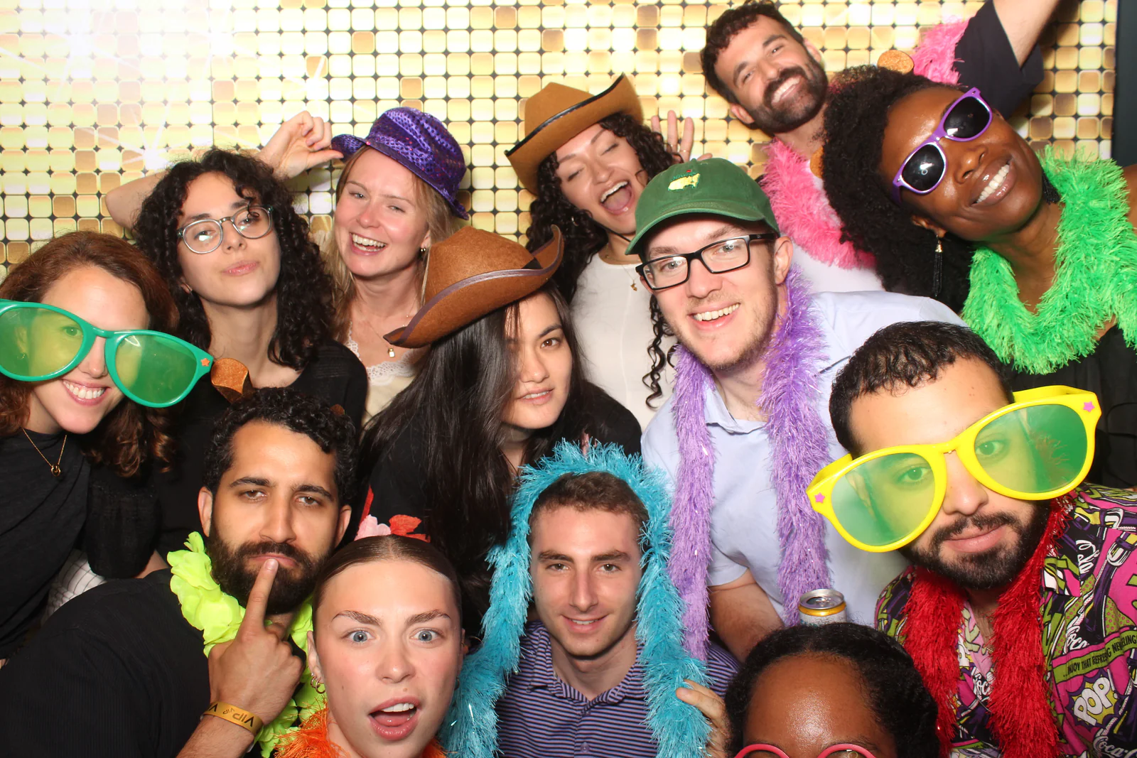 Open air photo booth rental NYC — large group with feather boas at a gold sequin backdrop