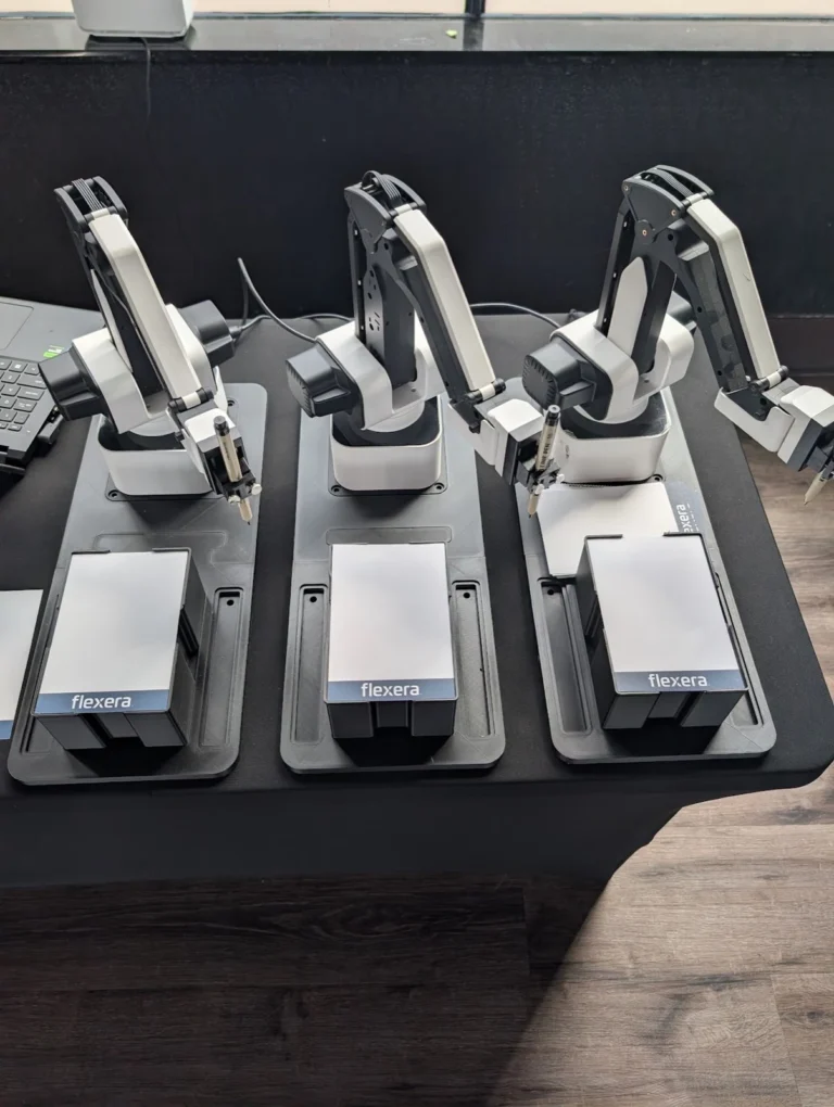 Sketch bot rental NYC — twin robot sketch artists drawing live AI portraits at a corporate trade show